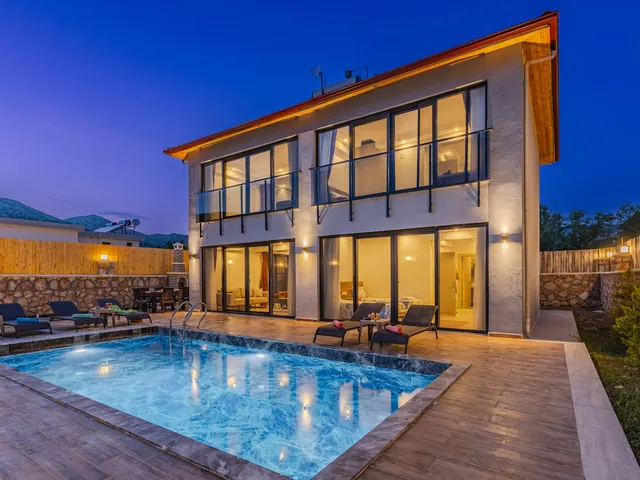 Modern luxury home with warm lit windows and a pool glowing blue at dusk