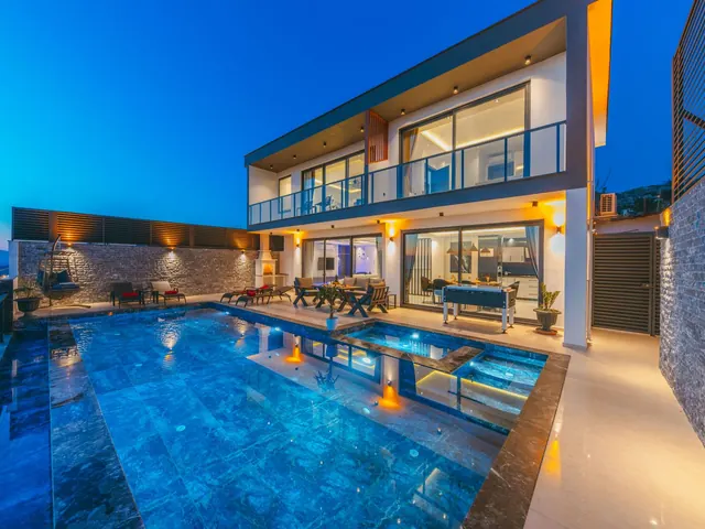 Modern villa at dusk with an illuminated pool and elegant terraces