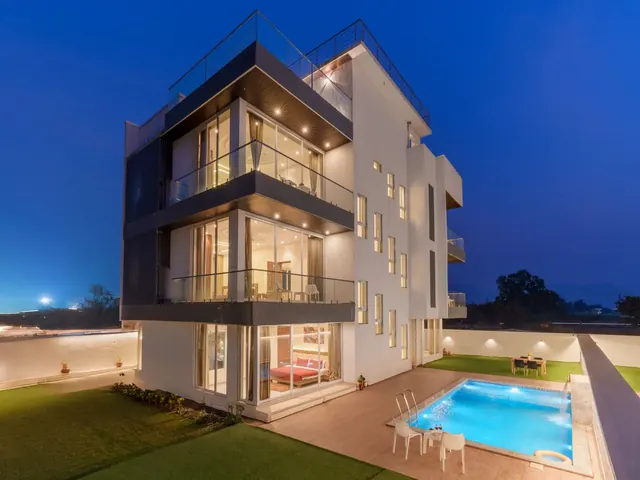 Contemporary villa with glass walls and a pool lit up against a deep blue twilight sky