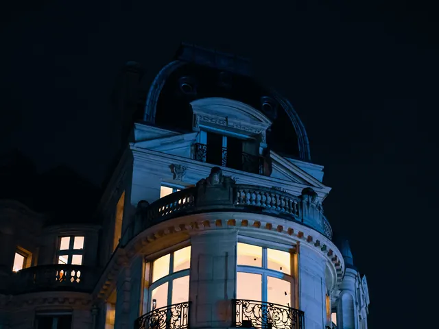 Upper floors of a stately mansion at night with warm lights glowing in the windows