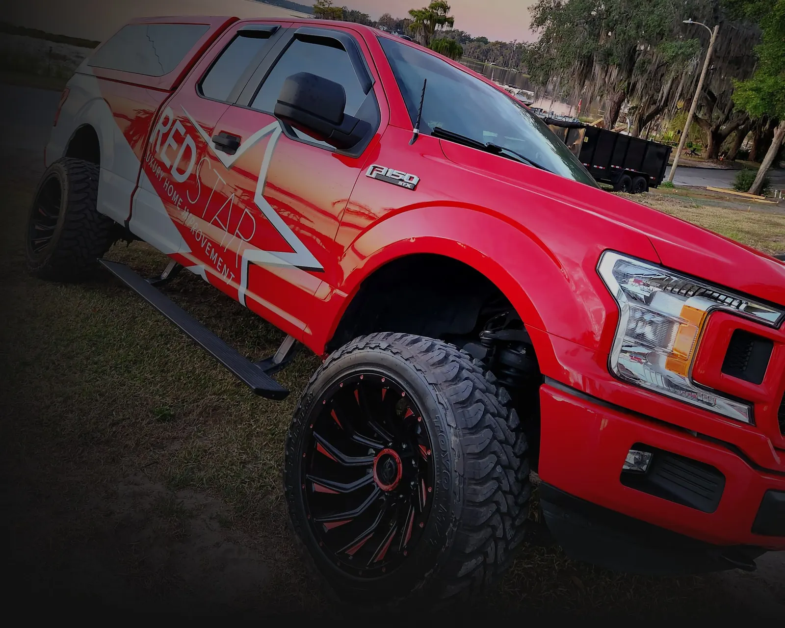 Red Star Luxury Homes red F-150 with the star wrap parked by the lake