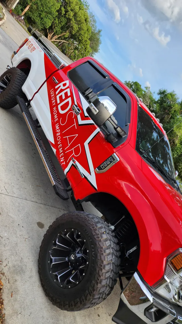 Tilted low front-quarter close-up of the red Red Star F-250 showing the star wrap and off-road tires