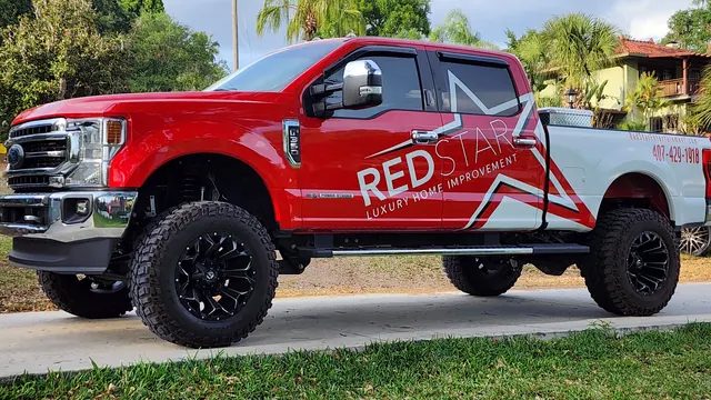 Lifted red and white Ford F-250 wrapped with the Red Star Luxury Home Improvement star logo, parked on a driveway