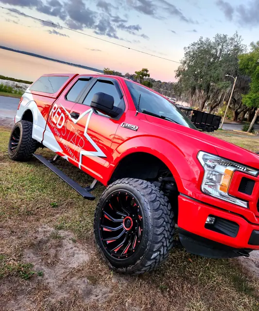 Red Star F-150 with the star wrap parked by a lake at sunset