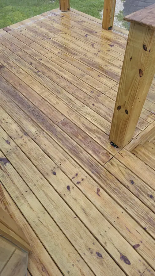 Finished pressure-treated wood deck with a sturdy corner post and freshly laid deck boards