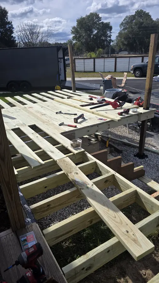 Pressure-treated wood deck frame under construction with joists, steps and tools laid out