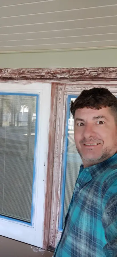 Smiling Red Star crew member taking a selfie beside window trim that has been stripped and prepped for paint